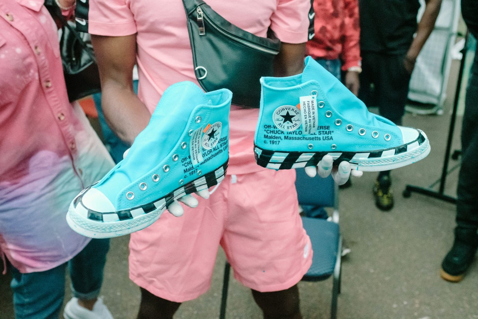 man holding blue-and-white Converse All-Star high-top sneakers